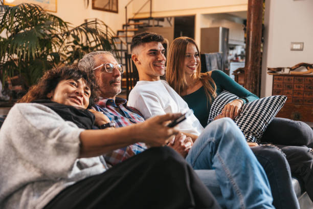 Happy family relaxing and watching TV together stock photo