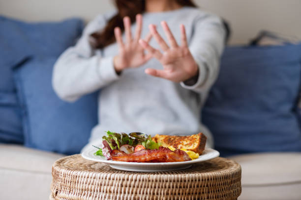 женщина, делающая знак руки, чтобы отказаться от пищи на столе для диеты и концепции здорового питания - dieting food rejection women стоковые фото и изображения