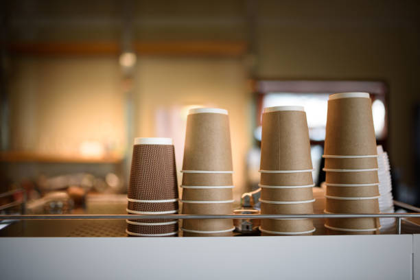 Degradable coffee paper glasses are standing on the top of the coffee machine in a cozy coffee shop. stock photo