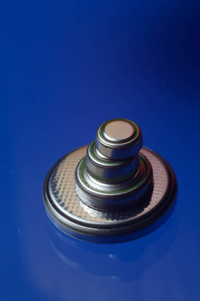 istock small button batteries of different sizes, highlighted in red and orange, lie against a blue background. close-up. 1344910822