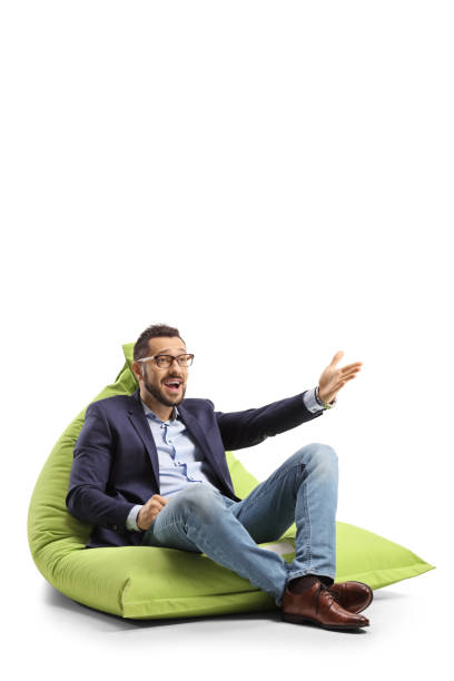 istock Young man sitting on a green bean bag chair and gesturing with hand 1344911732