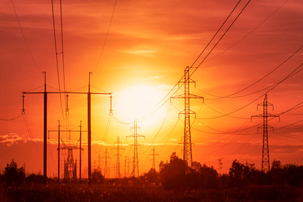 エネルギー危機:不穏な赤いトーンで夕日の背景に送電線 - fuel and power generation power line electricity pylon built structure ストックフォトと画像