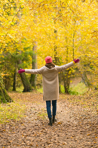 A woman walks in a beautiful autumn yellow forest and enjoys a walk