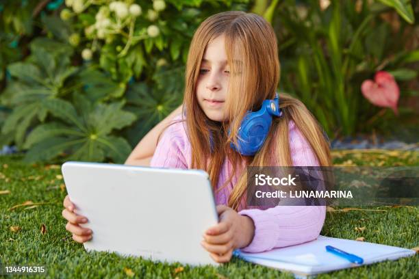 สาวผมบลอนด์เด็กกับแท็บเล็ตพีซีนอนอยู่บนสนามหญ้า ภาพสต็อก - ดาวน์โหลดรูปภาพตอนนี้ - กลางแจ้ง - การตั้งค่า, การถ่ายภาพ - ภาพ, การทำงานทางไกล
