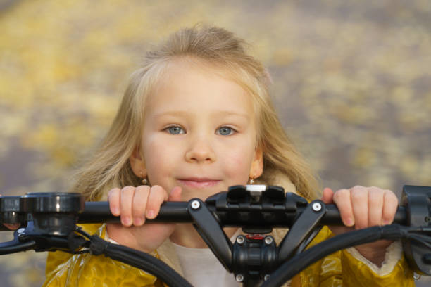 The child is even lower than the scooter Funny cute girl in the autumn public park. She is happy. Time for leisure and walking. She holds by hands on the steering wheel of an electric scooter. She is yet lower than the steering wheel. top view on people walking and cyclists riding stock pictures, royalty-free photos & images