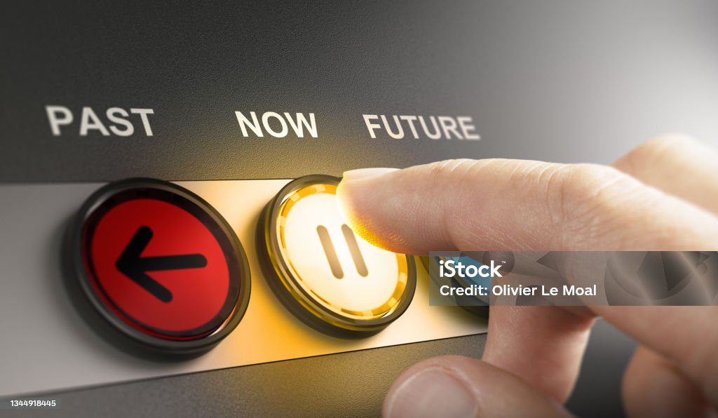 Time machine concept. Returning to the past, living in the present moment or in the future. Man pressing a yellow button with the word now printed on the top, to stop the time and live in the present moment. Composite image between a hand photography and a 3D background. Time Machine Stock Photo