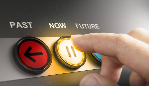 Time machine concept. Returning to the past, living in the present moment or in the future. Man pressing a yellow button with the word now printed on the top, to stop the time and live in the present moment. Composite image between a hand photography and a 3D background. push pause stock pictures, royalty-free photos & images