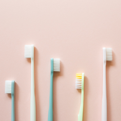 Colorful toothbrushes on pink background. top view, copy space