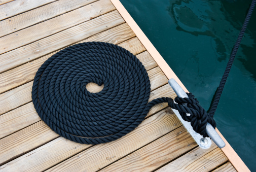 Black yacht's rope on dock.