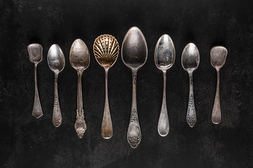 Silver cutlery on black background.Pile of vintage silverware and empty plates on dark grey background.  Top view point.