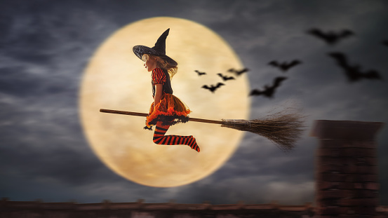 child flies as a witch to helloween with the moon in the background