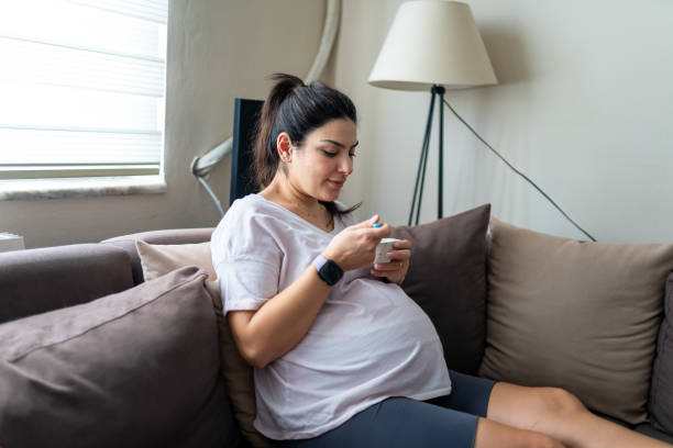 istock Pregnant woman eats pomegranate while watching TV at home 1344927617