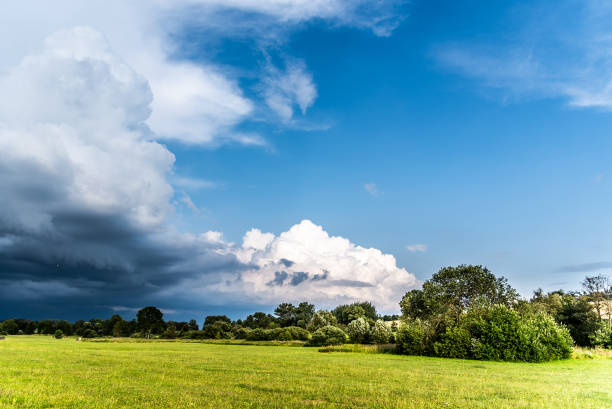 prima del temporale estivo. nuvole drammatiche in arrivo in un paesaggio verde e soleggiato - incoming storm foto e immagini stock