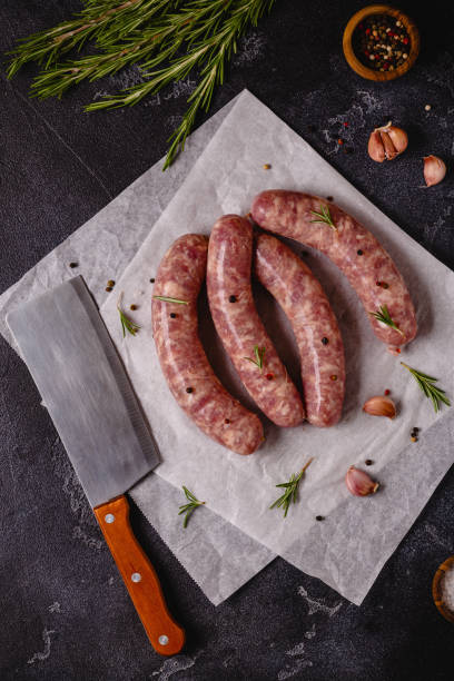istock Raw sausages and ingredients for cooking on a black stone table 1344928392