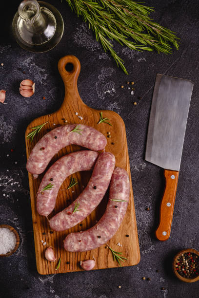 istock Raw sausages and ingredients for cooking on a black stone table 1344928417