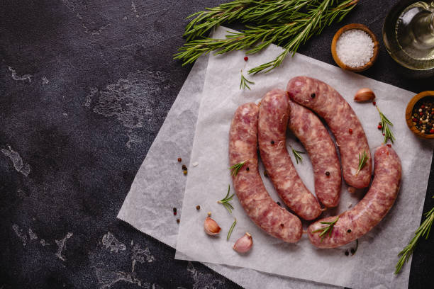 istock Raw sausages and ingredients for cooking on a black stone table 1344928653
