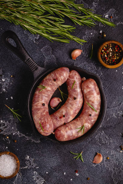 istock Raw sausages and ingredients for cooking on a black stone table 1344928741