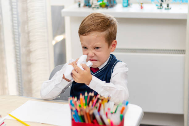 istock Cute boy first grader in school uniform at home during a break fooling around while sitting at his desk. Selective focus. Close-up 1344932253