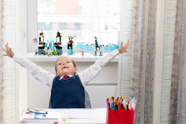 istock Cute boy first grader in school uniform at home during a break fooling around while sitting at his desk. Selective focus. Close-up 1344932306