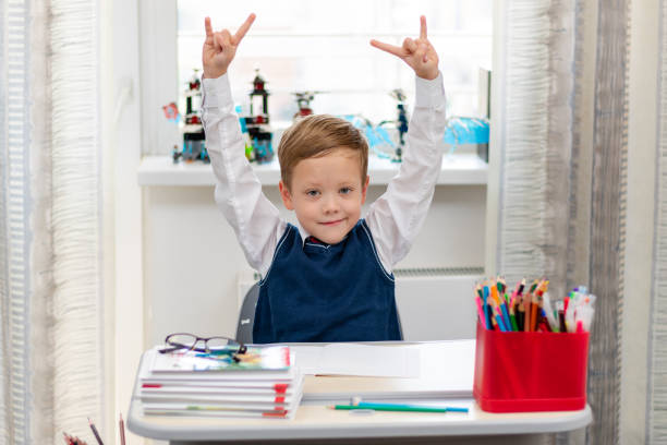 istock Cute boy first grader in school uniform at home during a break fooling around while sitting at his desk. Selective focus. Close-up 1344932308