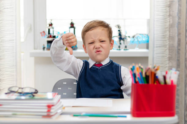 istock Cute boy first grader in school uniform at home during a break fooling around while sitting at his desk. Selective focus. Close-up 1344932312
