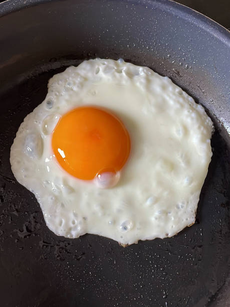 istock Full frame image of sunny side up fried egg sat frying in non-stick frying pan, elevated view 1344933865