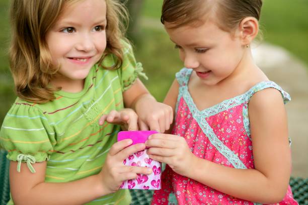 Two little twin sisters playing with pink box outdoor