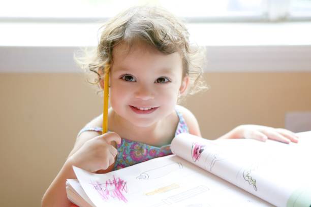 little toddler girl writing at school desk - child thinking writing little girls imagens e fotografias de stock