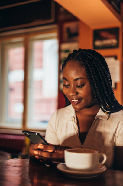 istock African american woman using smartphone while drinking espresso coffee in a cafe 1344937073