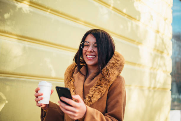 istock Young hispanic woman using smartphone and drinking coffee takeaway 1344937099