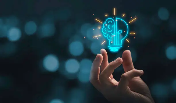 Photo of Hand holding drawing virtual lightbulb with brain on bokeh background for creative and smart thinking idea concep