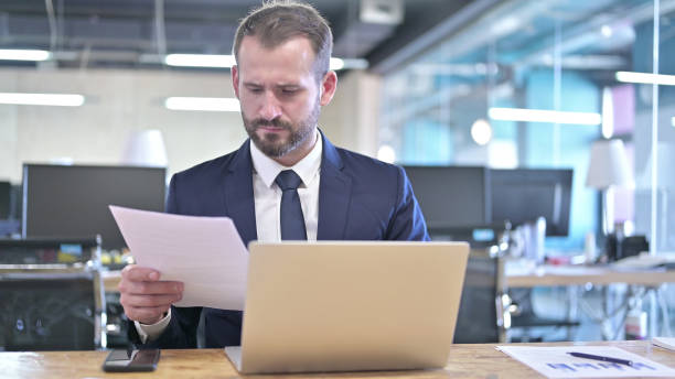istock Young Businessman reading Documents on Office Desk 1344945628