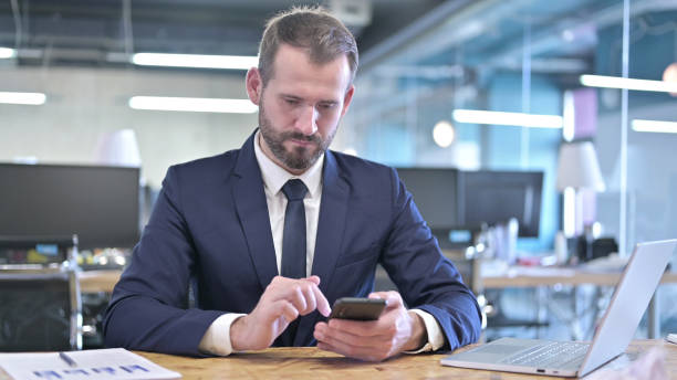 istock Young Businessman using Smartphone on Office Desk 1344945916