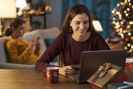 Happy young woman doing online shopping at Christmas using a credit card