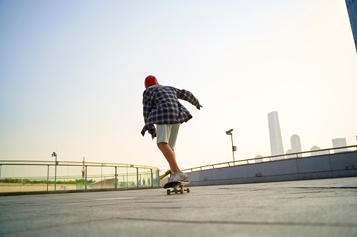 teenage asian child skateboarding outdoors on a pedestrian bridge