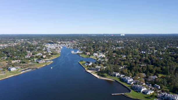 An aerial, high angle shot over Bayshore, New York showing the beautiful waters of the Great Cove on a sunny morning. A high angle drone shot over Bayshore, New York. The shot shows the waters of the Great Cove on a sunny morning and the beautiful waterfront properties in the Long Island neighborhood. Bayshore is a Hamlet in the town of Islip in Suffolk County, New York. bay of water stock pictures, royalty-free photos & images