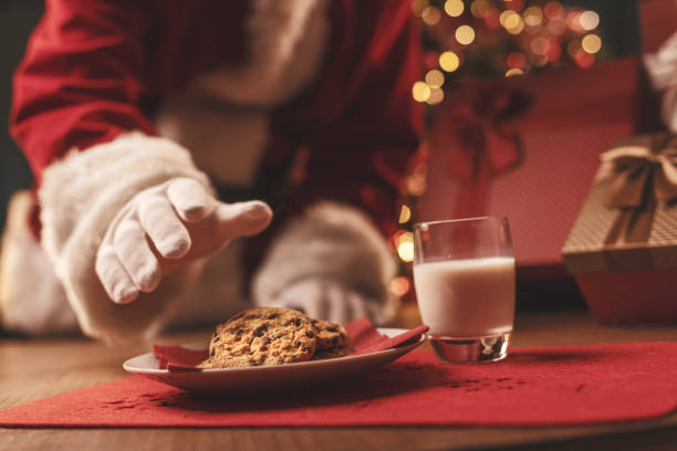 Santa Claus having a delicious snack Santa Claus having a delicious snack, he is eating cookies and drinking milk, Christmas and holidays concept santa claus stock pictures, royalty-free photos & images
