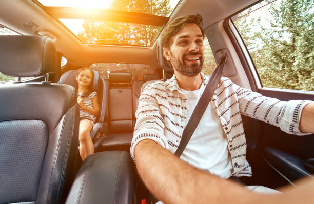 Family with dog in the car Child cute girl in a car seat protected by seat belts with her dad going in the car for the weekend. Leisure, travel, tourism. car interior stock pictures, royalty-free photos & images