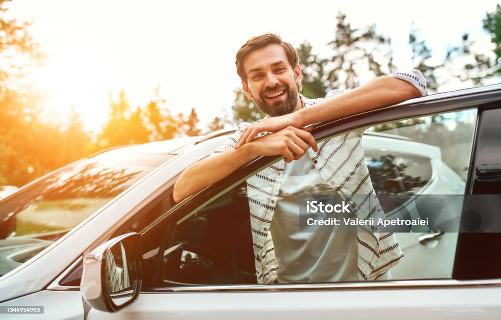 Family with dog in the car A smiling man stands near the car on the background of the forest. Purchase, car rental. Rest in nature, weekend. Car Stock Photo