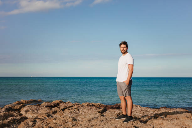 istock Young man standing smiling at the camera in front of the beach 1344955395