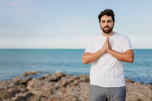 istock Praying handsome young man with hands on chest, closed eyes and grateful face gesture in front of the sea 1344955503