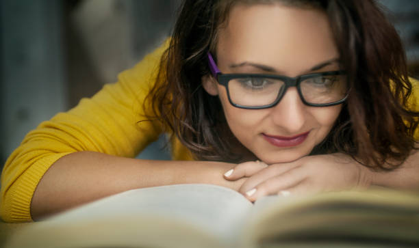 istock Woman in yellow, lying down, reading book 1344955577