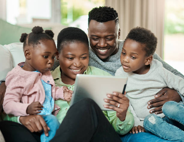 istock Cropped shot of an affectionate young family of four using a tablet while sitting on a sofa in their living room at home 1344959052