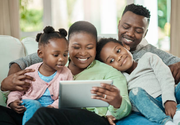 istock Cropped shot of an affectionate young family of four using a tablet while sitting on a sofa in their living room at home 1344959055