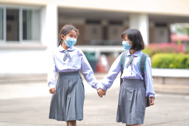 Cheerful Asian children student in student uniform back to school with medical face mask after COVID-19 pandemic. Back to School Concept Stock Photo stock photo