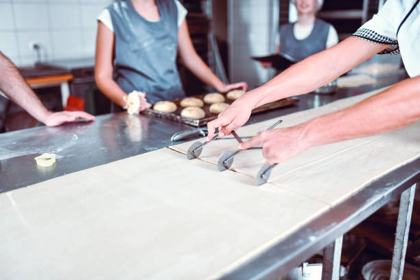istock Baker Showing Apprentices How To Cut Flattened Dough And Make Pastries 1344960666