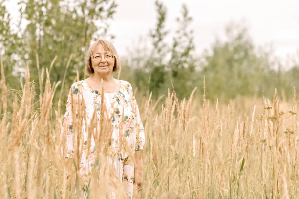 istock An elderly woman in the tall grass with spikelets. Autumn 1344960837