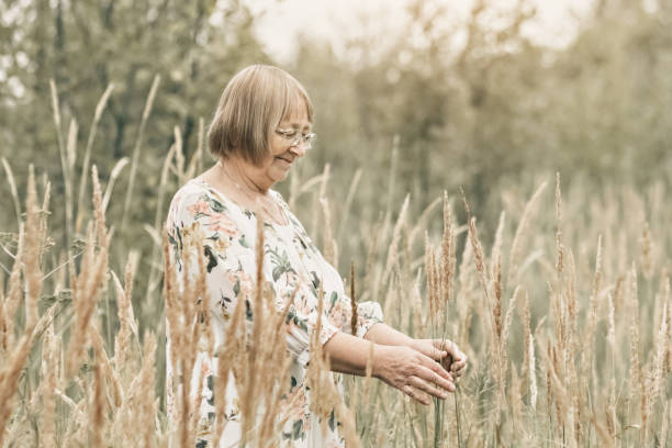 istock An elderly woman in the tall grass with spikelets. Autumn 1344961337