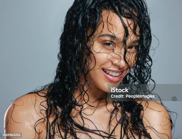 Studio Portrait Of An Attractive Young Woman Posing With Wet Hair Against A Grey Background Stock Photo - Download Image Now