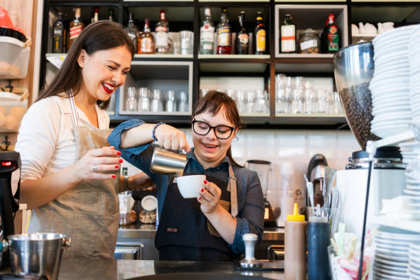 Young woman with Down Syndrome working at cafe preparing coffee Young woman with Down Syndrome working at cafe disability stock pictures, royalty-free photos & images